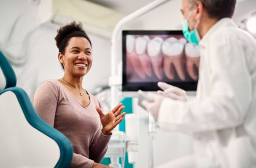 A happy female patient consulting with her dentist at a dental office.