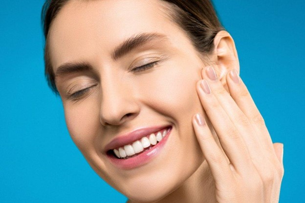 A woman with a beautiful smile touching her cheeks after restorative
dental work A woman with a beautiful smile touching her cheeks after restorative
dental work