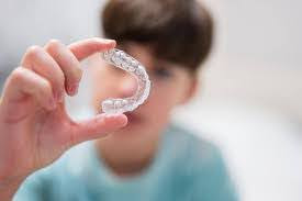  A young boy holding up his Invisalign for kids