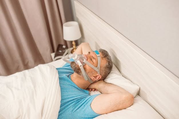  A Picture Showing A Man Using A Sleep Apnea Machine While Peacefully Lying on the Bed
