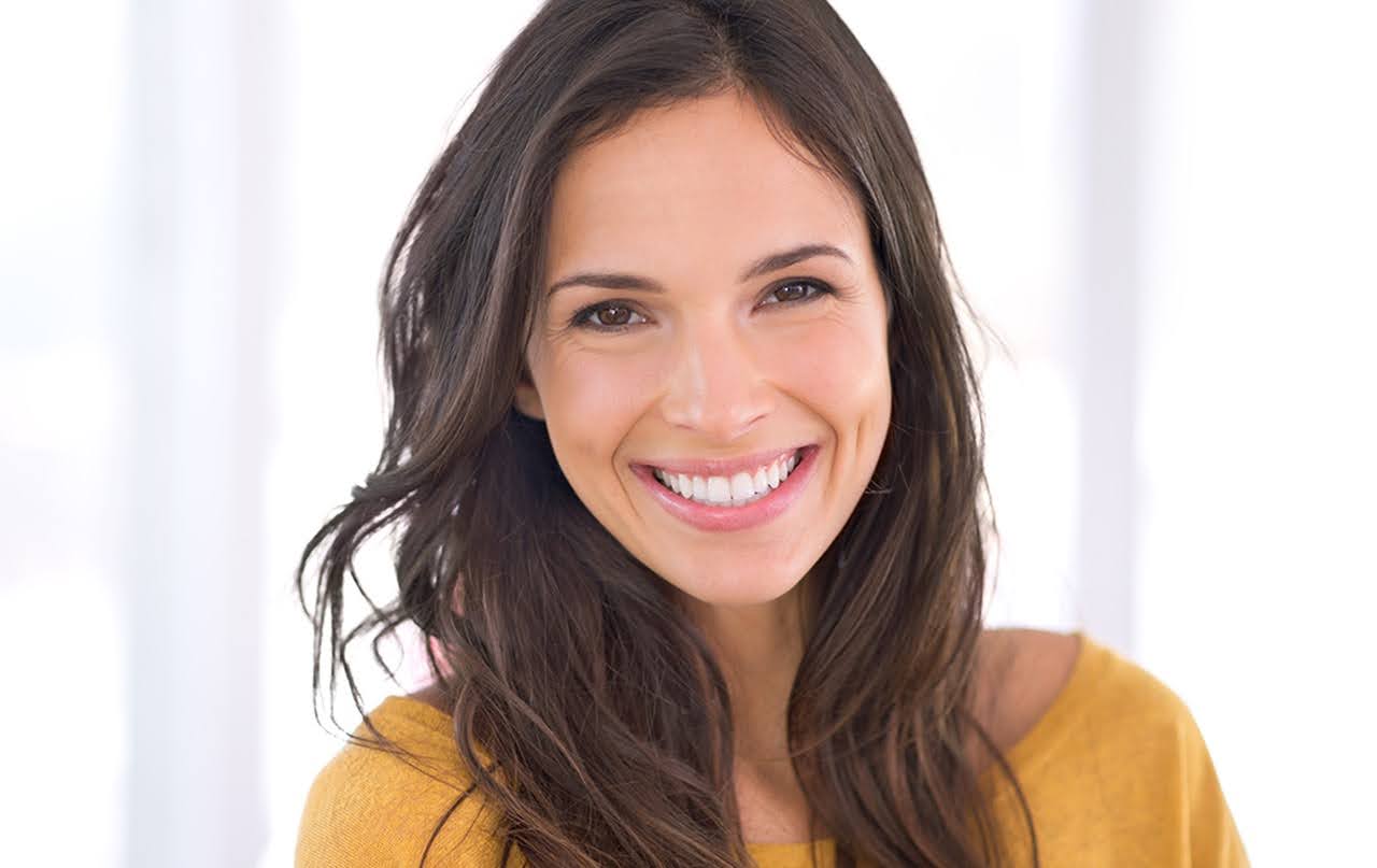  A smiling young woman showcasing her healthy gums and teeth after an effective gum treatment with ozone