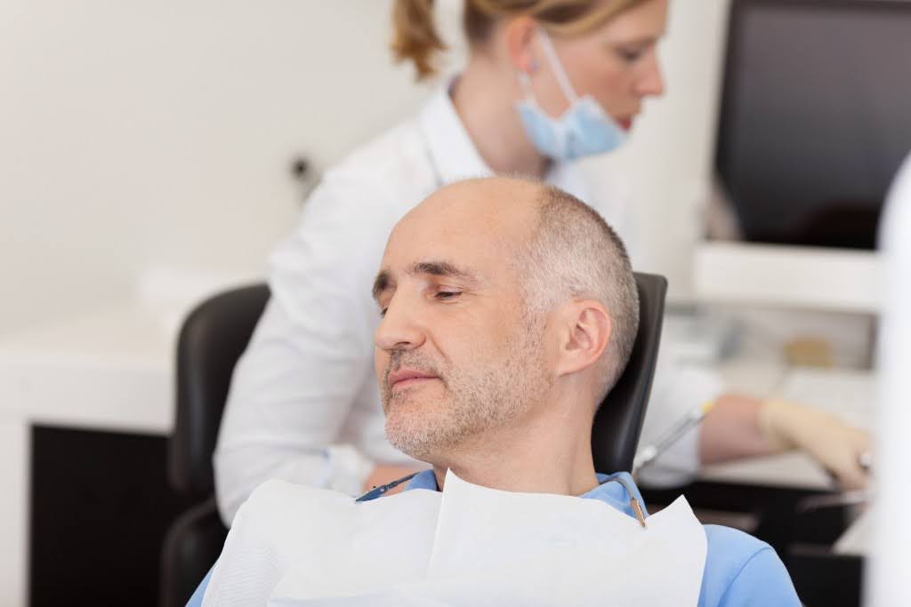  An elderly man at the dentist’s chair undergoing ozone therapy for gums
