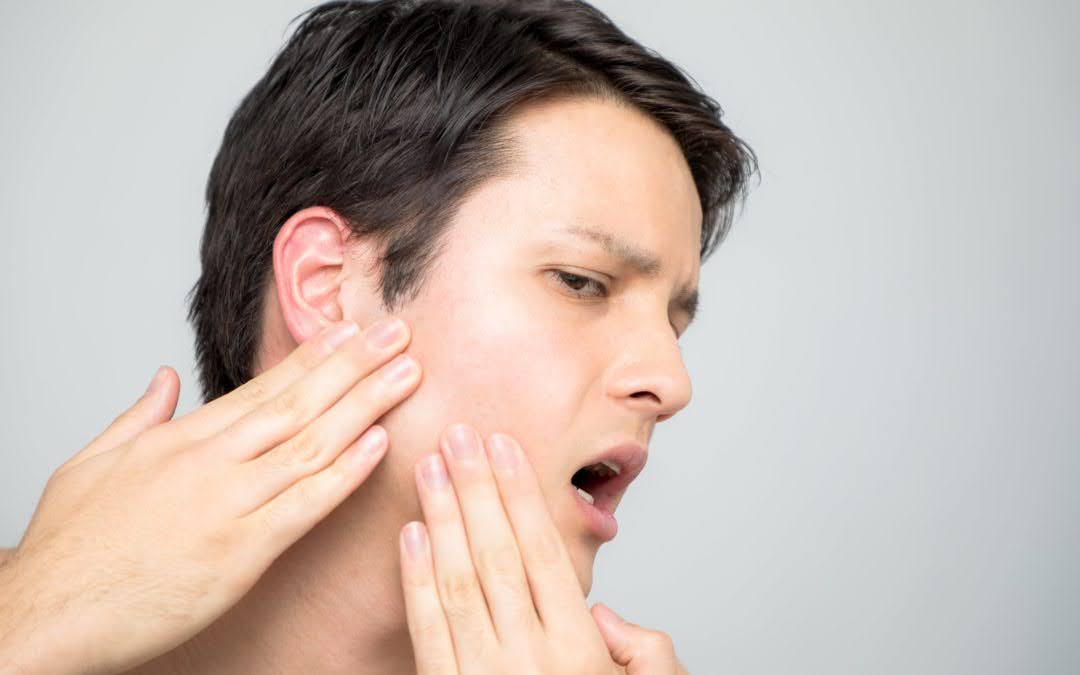   A Man Curiously Running His Fingers Over the Jaw Pain