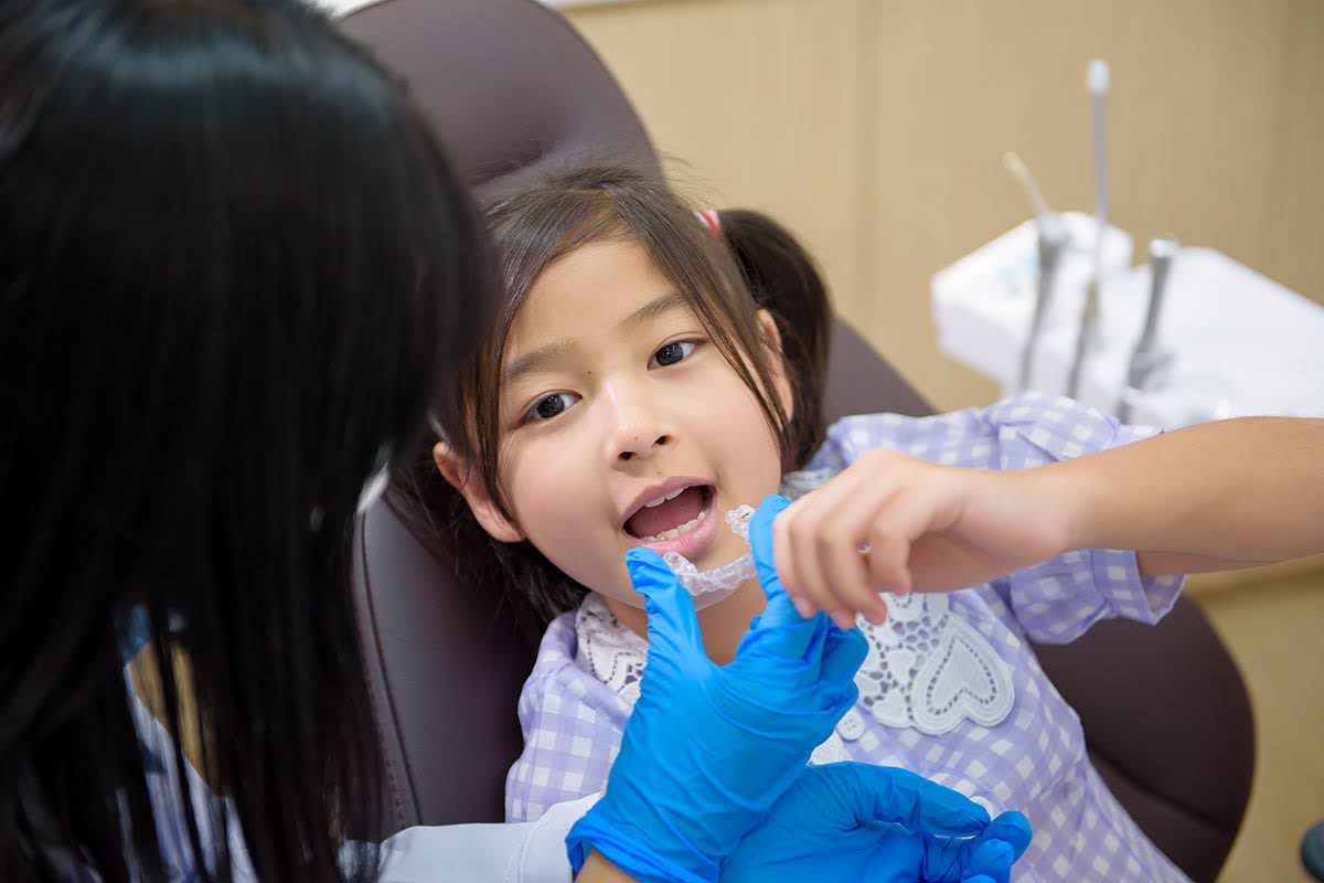  A Dentist Trying to Fit Invisalign into a Child's Mouth