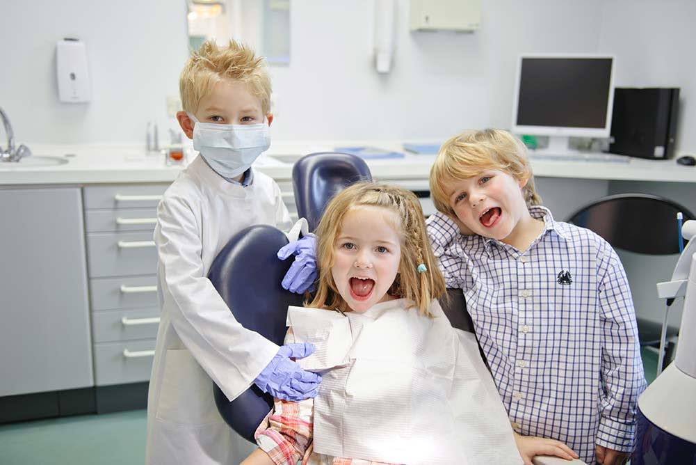  3 kids playing the patient, parent, and the dentist