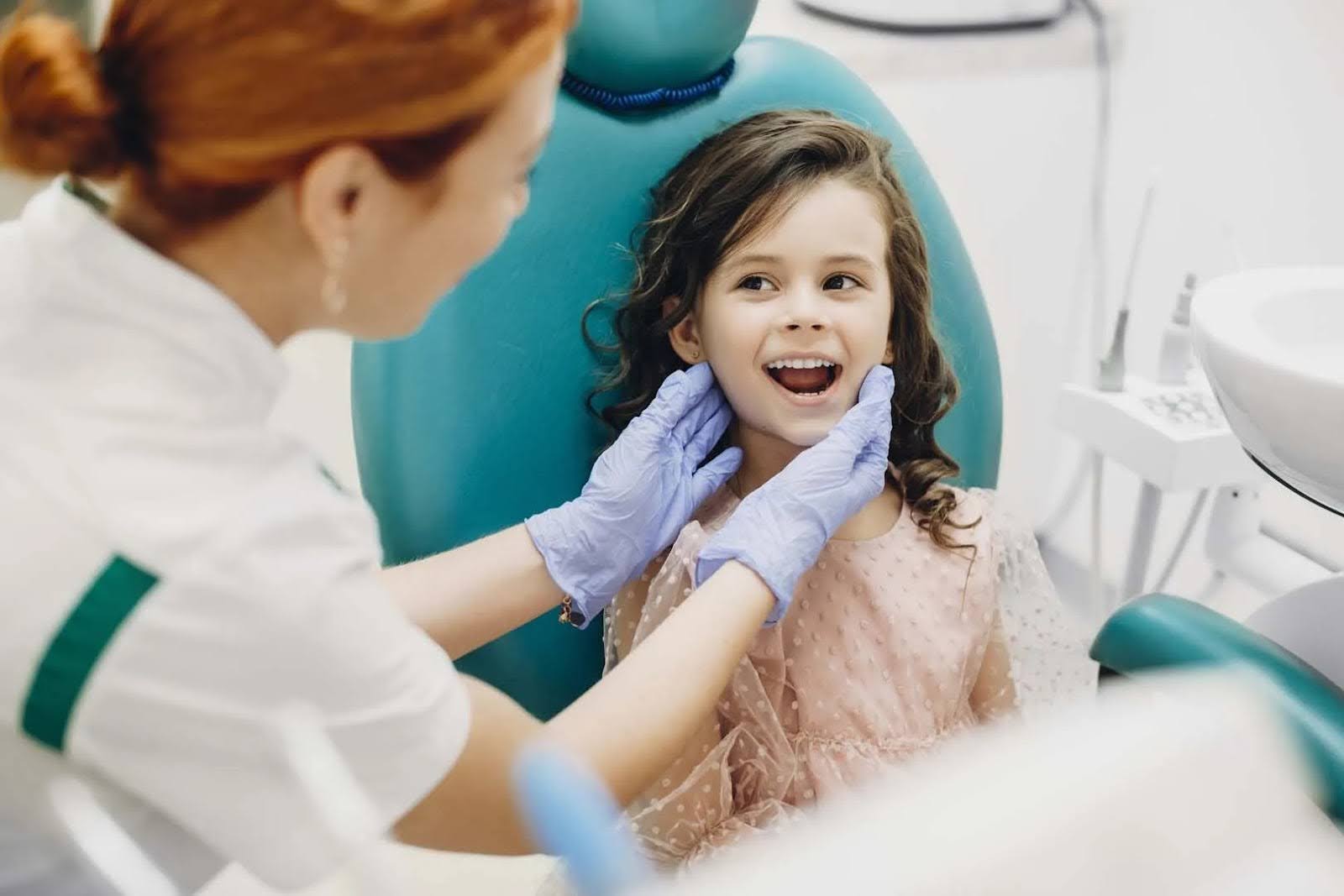   A young girl in a dentist chair at a dentist's office who specializes in pediatric tooth extraction near her.