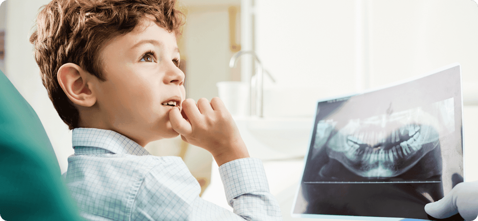  A young boy in a dentist chair being shown an X-ray